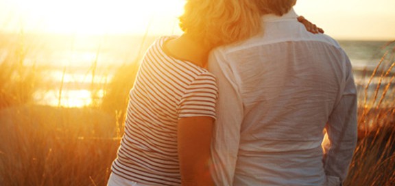 Elderly couple looking at a beach during sunset.