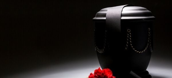 black urn with red rose against black background