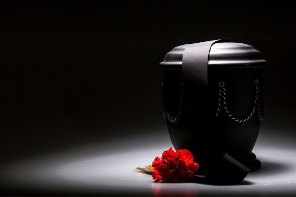 black urn with red rose against black background