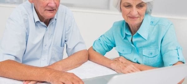 Elderly couple sitting down looking at laptop