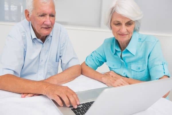 Elderly couple sitting down looking at laptop