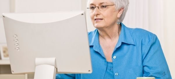 Woman sitting at desk with cup of tea looking at computer