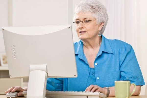 Woman sitting at desk with cup of tea looking at computer